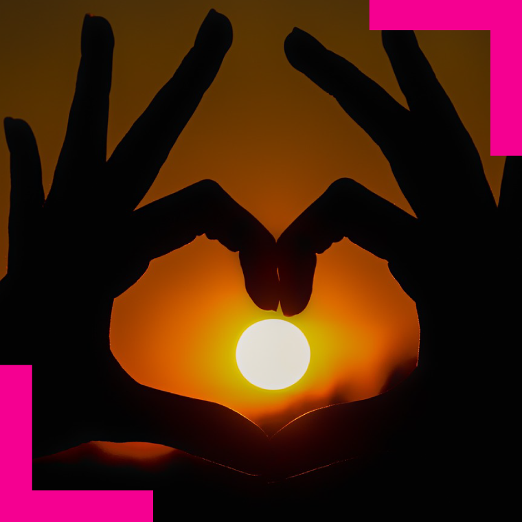 Silhouetted hands form a heart shape around a glowing sunset sun   Romantic sunset moment conveyed by finger heart gesture